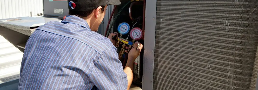 HVAC technician servicing a condenser unit in Mayfield Heights